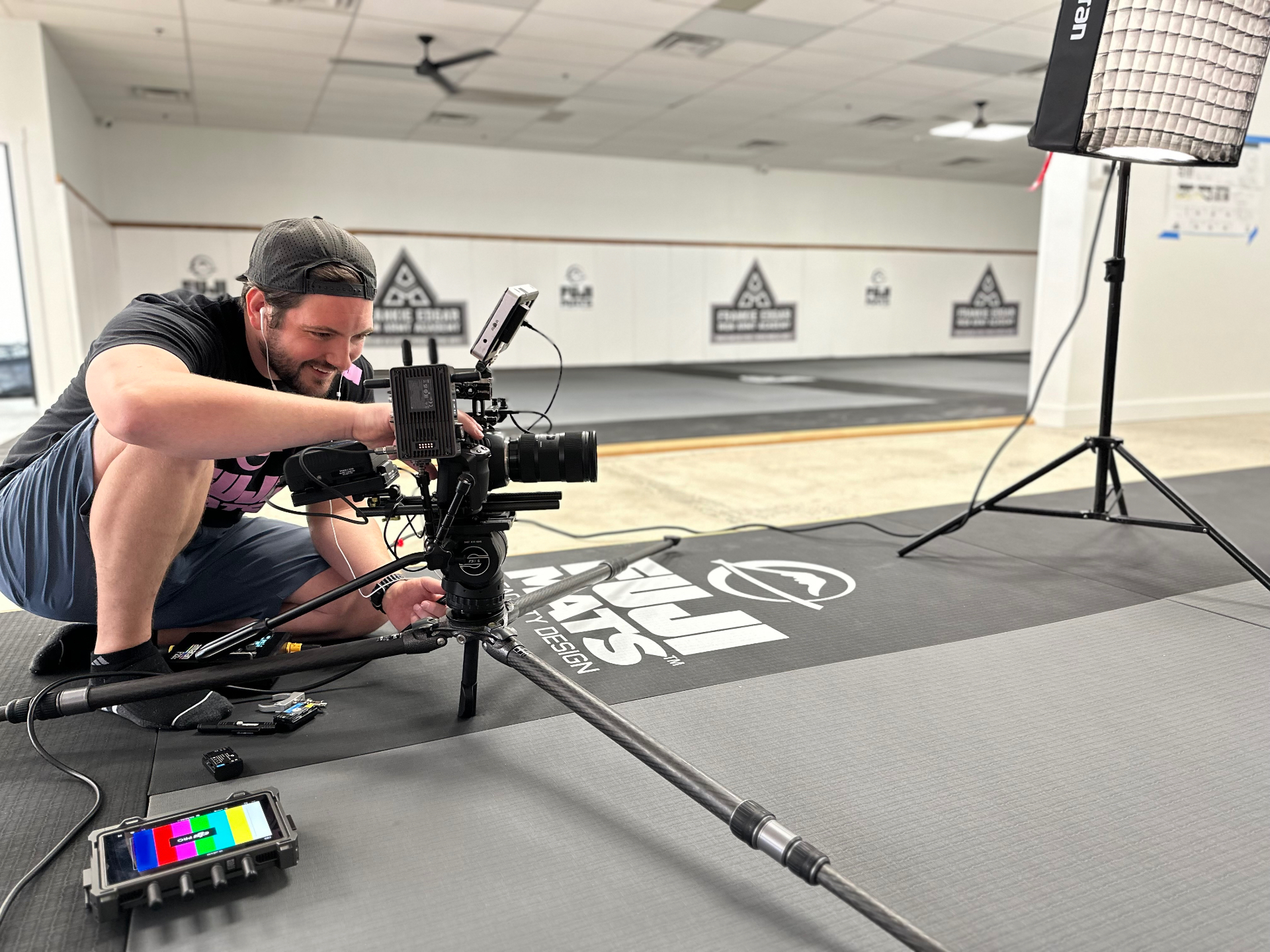 Spencer kneeling beside a cinema camera on a slider, framing a shot on Fuji mats